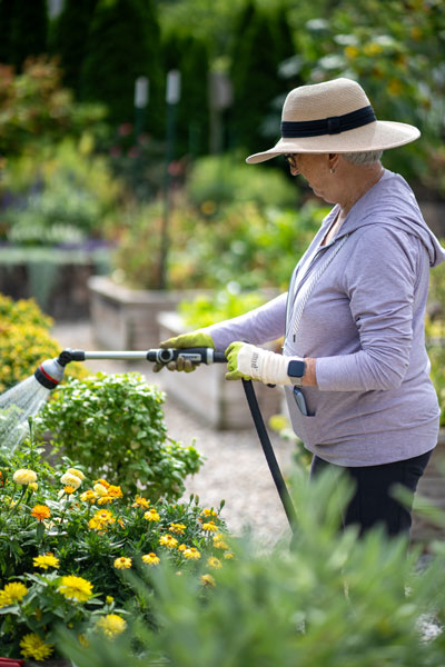 Resident waters flowers in her raised bed garden.