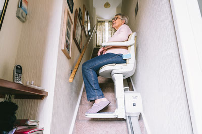 Senior woman using automatic stair lift at home