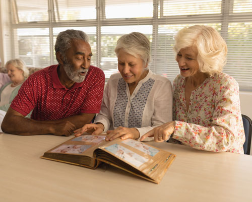 Group of seniors look at photo album in memory care community
