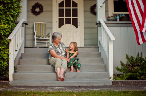 An older woman who is aging in place on the front porch of her home with her granddaughter.