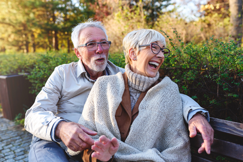 Senior couple laughing on a park bench