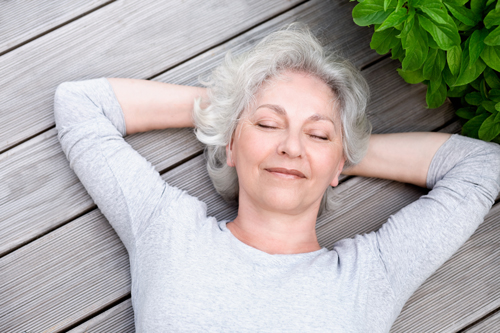 Older woman relaxing on a deck, showing peace of mind