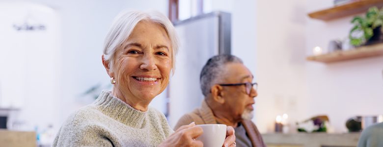 Senior woman with a coffee cup enjoying conversation with friends
