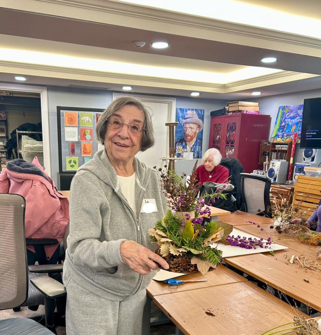 Senoir woman in workshop showing off plant arrangement.