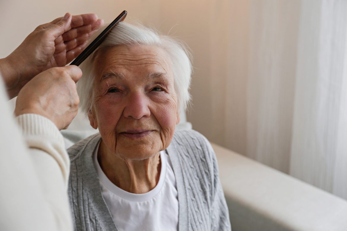 A nursing home Resident having her hair groomed.