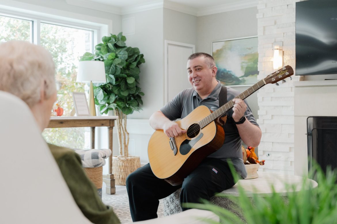 Volunteer playing guitar at Rowan House Memory Care.