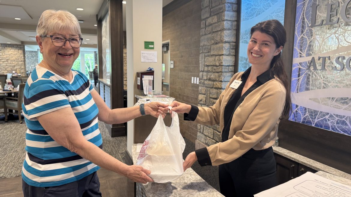 A culinary department team member hands Resident Sandy W. a meal she ordered through the online ordering system at Friendship Village of Dublin.