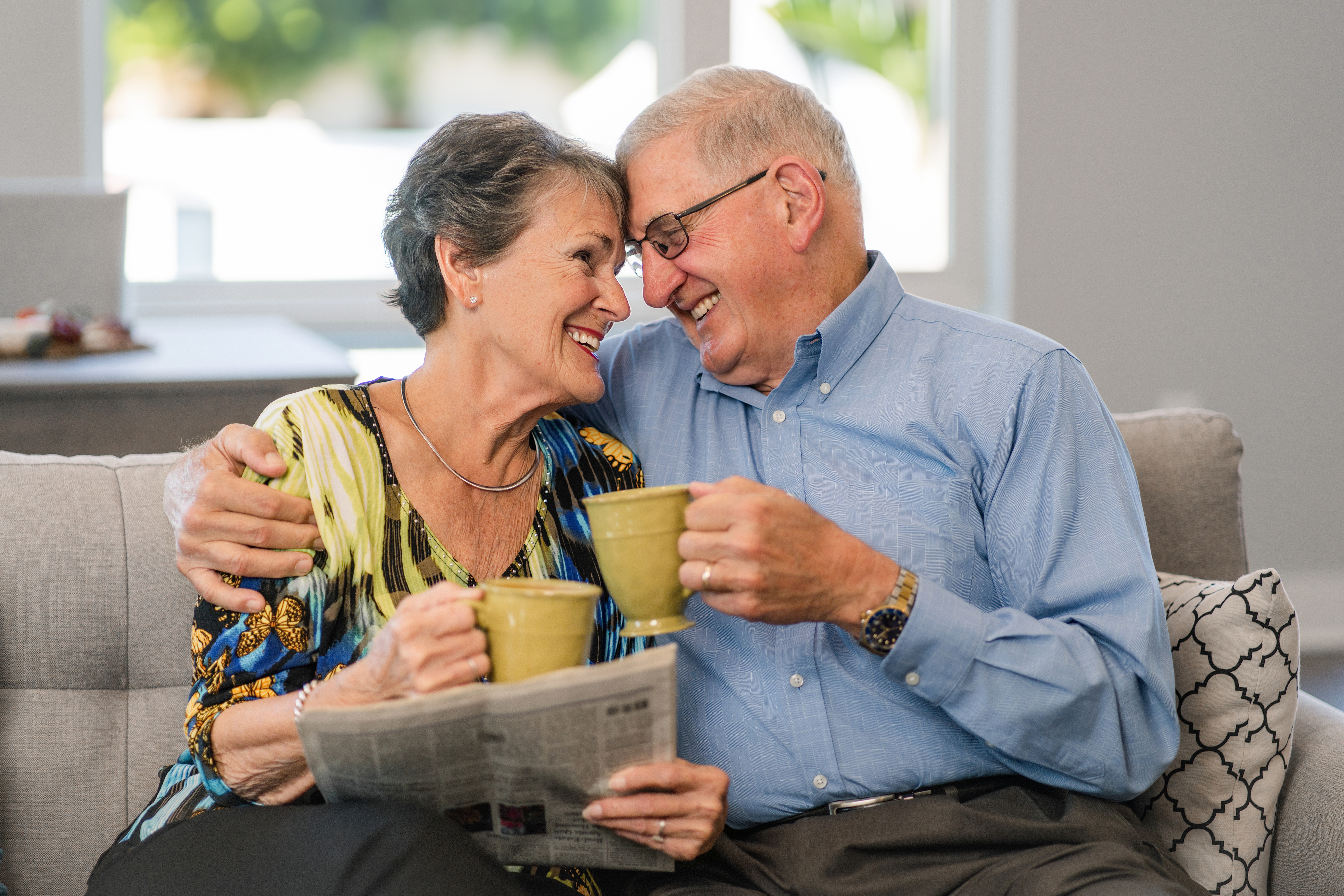 Two Friendship at Home members sit worry-free with their coffee on the couch.